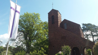 Kreuzkirche Kahl mit Fahne lila Kreuz auf weißen Grund